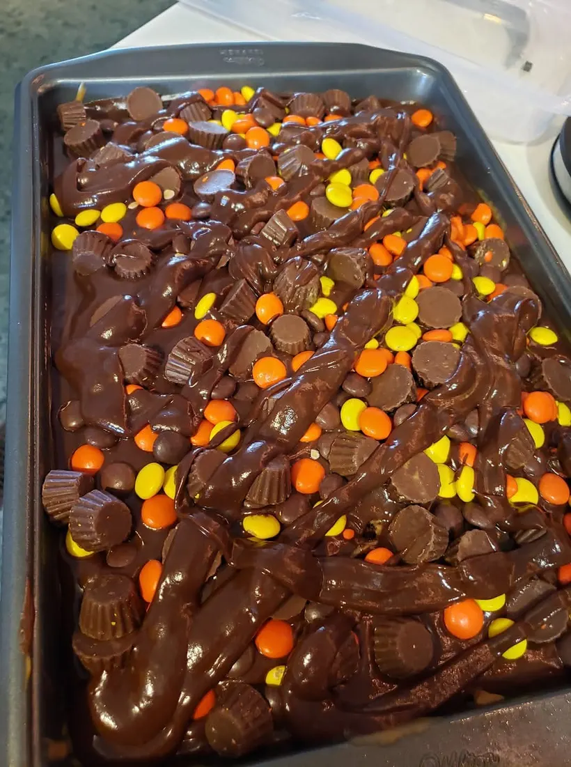 Tray of peanut butter cup brownies photographed on a stovetop under harsh indoor light